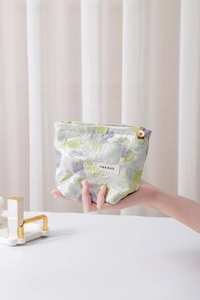 Detail of floral jacquard cosmetic bag featuring flower zipper pull and gold zipper