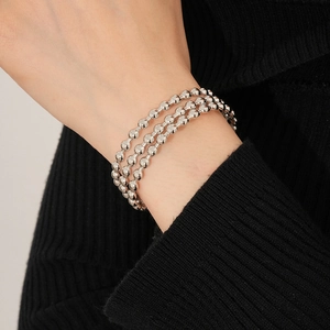 Dettaglio di un bracciale a tre strati con sfere d'argento indossato al polso