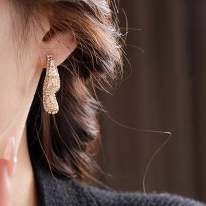 Detailed view of luxury gold zircon teardrop earrings worn on an ear showing fine craftsmanship