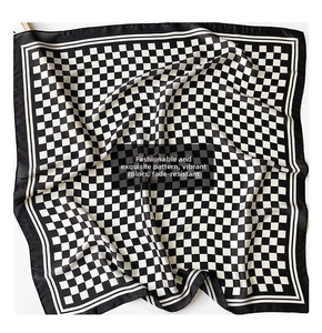 Detailed close-up of a black and white checkerboard silk scarf with satin texture finish