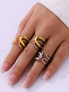 Close-up of minimalist gold and silver layered U-shaped stainless steel rings on a hand
