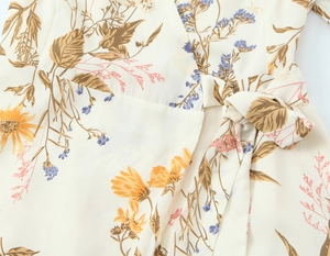Detail of waist tie-up on floral wrap dress with yellow sunflower print and crepe texture