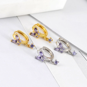 Detailed macro view of gold and silver butterfly hoop earrings with purple zircon crystals