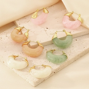 Detail showing four pairs of U-shaped marble resin earrings on a stone base with silk