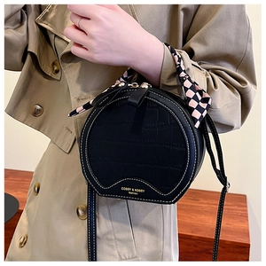 Detailed shot of black crocodile pattern circular bag with silk scarf on handle