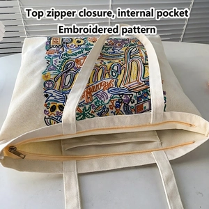 Cream embroidered canvas tote bag with top zipper and inner pocket shown from top view