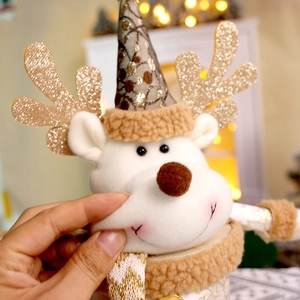 Dettaglio di cervo natalizio in peluche con corna dorate e cappello a punta a pois