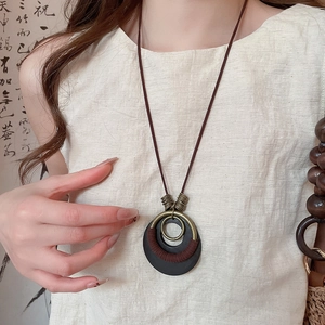 Detail of vintage wooden pendant necklace with bronze metal rings and rustic cord wrap