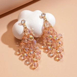 Detail of gold earrings featuring tiered pink crystal beads and clear faceted stones
