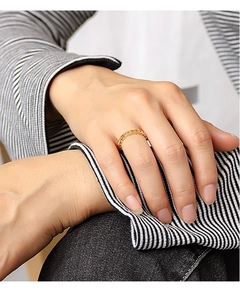 Detailed close-up of a golden chain-link heart ring worn on a model's hand