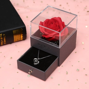 Detail of grey gift box with red rose and heart necklace under acrylic lid