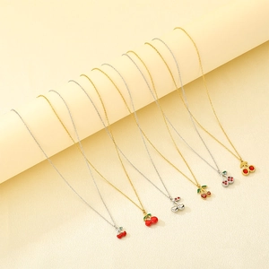 Detail of sweet cherry pendant necklaces in gold and silver finishes on a display stand
