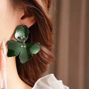 Detail view of green resin flower earrings with sparkling rhinestones on female model