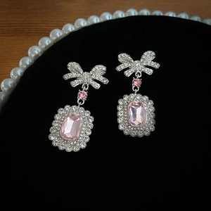 Vue détaillée de boucles d'oreilles nœud en argent avec cristal rose et strass brillants