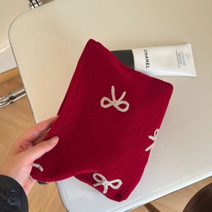 Detailed texture of red corduroy clutch bag with white knitted bow embroidery decorations