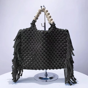 Detail of woven green macrame phone bag featuring long fringe and light wood bead handles