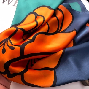 Detailed macro shot of floral print silk scarf showing satin texture and rolled hem