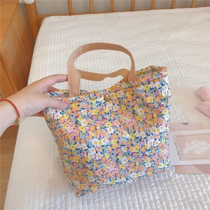 Detail of floral lunch bag featuring soft cotton fabric, khaki handles, and metal snap button