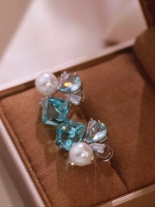 Macro detail of silver stud earrings with square blue zircon and round white pearls