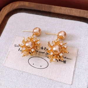 Detail of 18K gold plated earring with champagne pearl and radiant firework sunburst