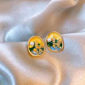 Detail of French vintage floral enamel earrings with pearls on soft silk background