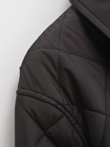 Close-up of high-quality diamond quilting and shoulder seam details on black cotton coat