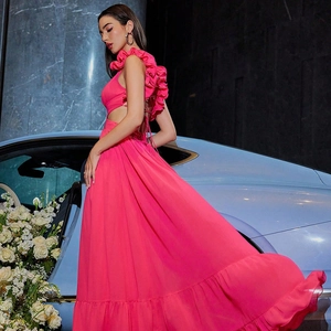 Détail d'une robe maxi en mousseline fuchsia avec dos nu et volants près d'une auto