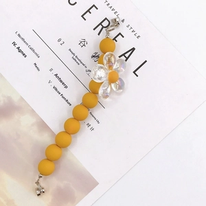 Close-up of yellow frosted beads and acrylic flower pendant with silver metal clasps