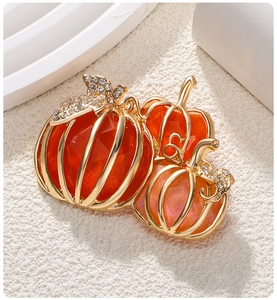 Detailed close-up of three orange crystal pumpkin brooches with sparkling rhinestone leaves
