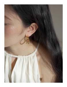 Close-up of gold layered twisted hoop earrings worn by a model in a natural light setting