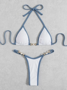 Flat lay of ribbed white bikini with blue trim and golden ring pearl details