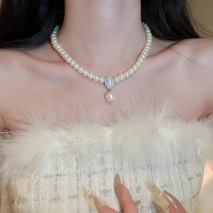 Close-up of elegant pearl necklace with teardrop zircon pendant on a female model