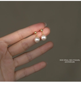 Detail of S925 sterling silver pearl earrings being held to show size and luster