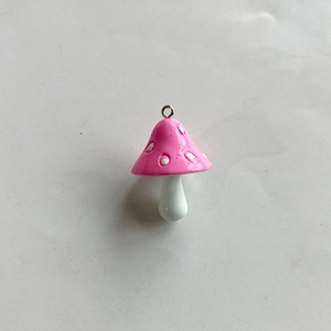 Detailed view of pink resin mushroom pendant with white dots and metal ring attachment