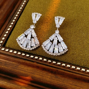 Close-up of silver fan-shaped earrings with zircon crystals on green velvet