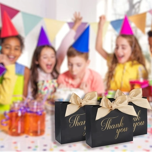 Détail de sacs cadeaux noirs avec ruban doré pour remerciements et mariages