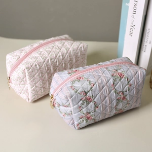 Quilted floral makeup bags in pink and blue with gold zippers for travel storage