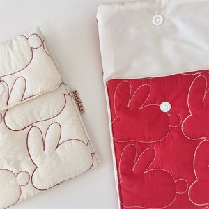 Close-up of quilted storage pouches with rabbit embroidery and white snap buttons