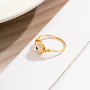 Detailed view of handmade gold wire-wrapped ring featuring a white shell evil eye stone