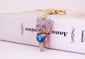 Detailed view of lucky cat keychain with blue faceted gemstone and white rhinestones