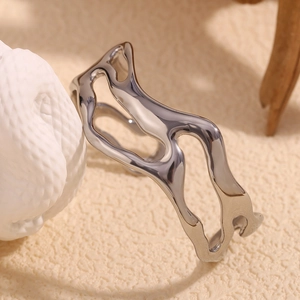 Macro shot of silver wave cutout bangle showing irregular polished hollow metal details