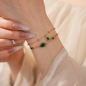 Détail d'un bracelet double couche en chaîne dorée avec pendentifs en malachite verte
