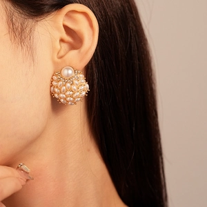 Vintage style gold pearl earrings with rhinestones shown on a model's ear