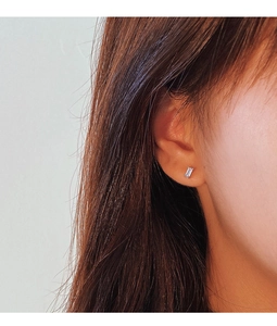 Close-up of minimalist silver rectangular zircon stud earrings worn by a model