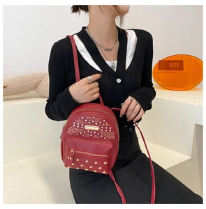 Detail view of red PU leather mini backpack with gold rivets and headphone jack hole