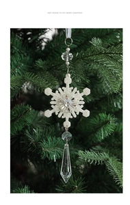 Close-up of sparkling acrylic snowflakes with glitter hanging on a green Christmas tree