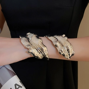 Detailed view of silver metallic leaf cuff bracelet with wrinkled texture on a model arm