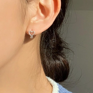 Close-up of S925 sterling silver heart stud earrings with a beaded texture on ear