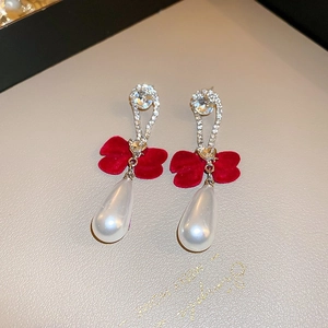 Detail of red velvet bow earrings with teardrop pearls and sparkling rhinestones