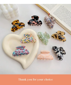 Flat lay of small acetate hair claws in tortoise shell and marble patterns on ceramic tray